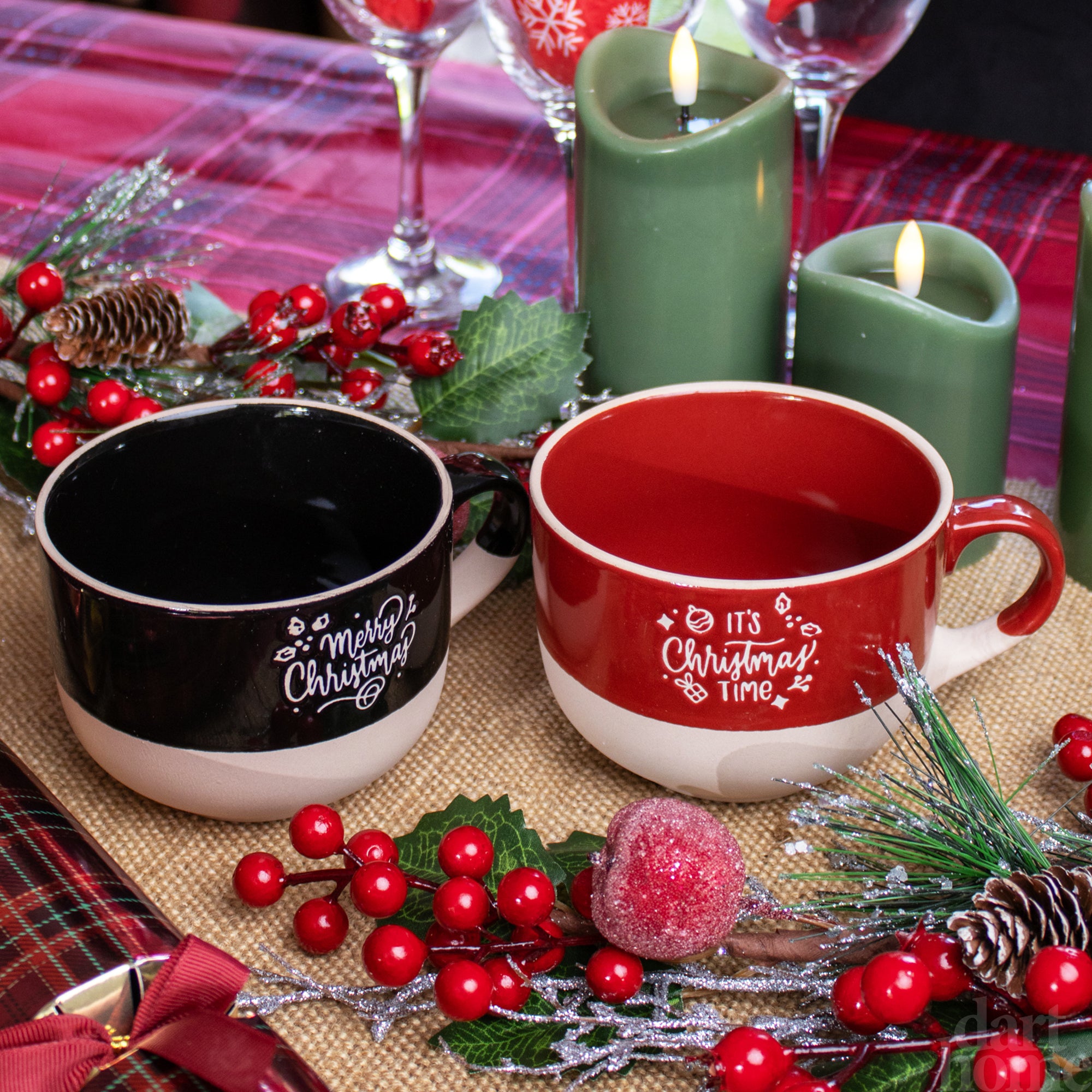 Two red and black Christmas-themed soup bowls with decorative placemats and festive decorations around them.