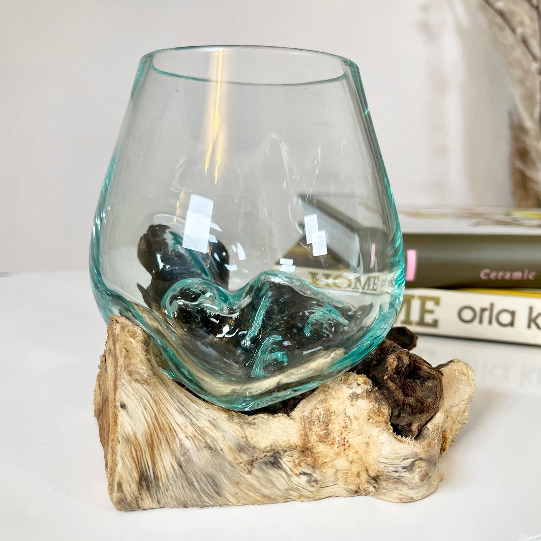 Molten glass decorative bowl placed on a rustic teak root wood stand.