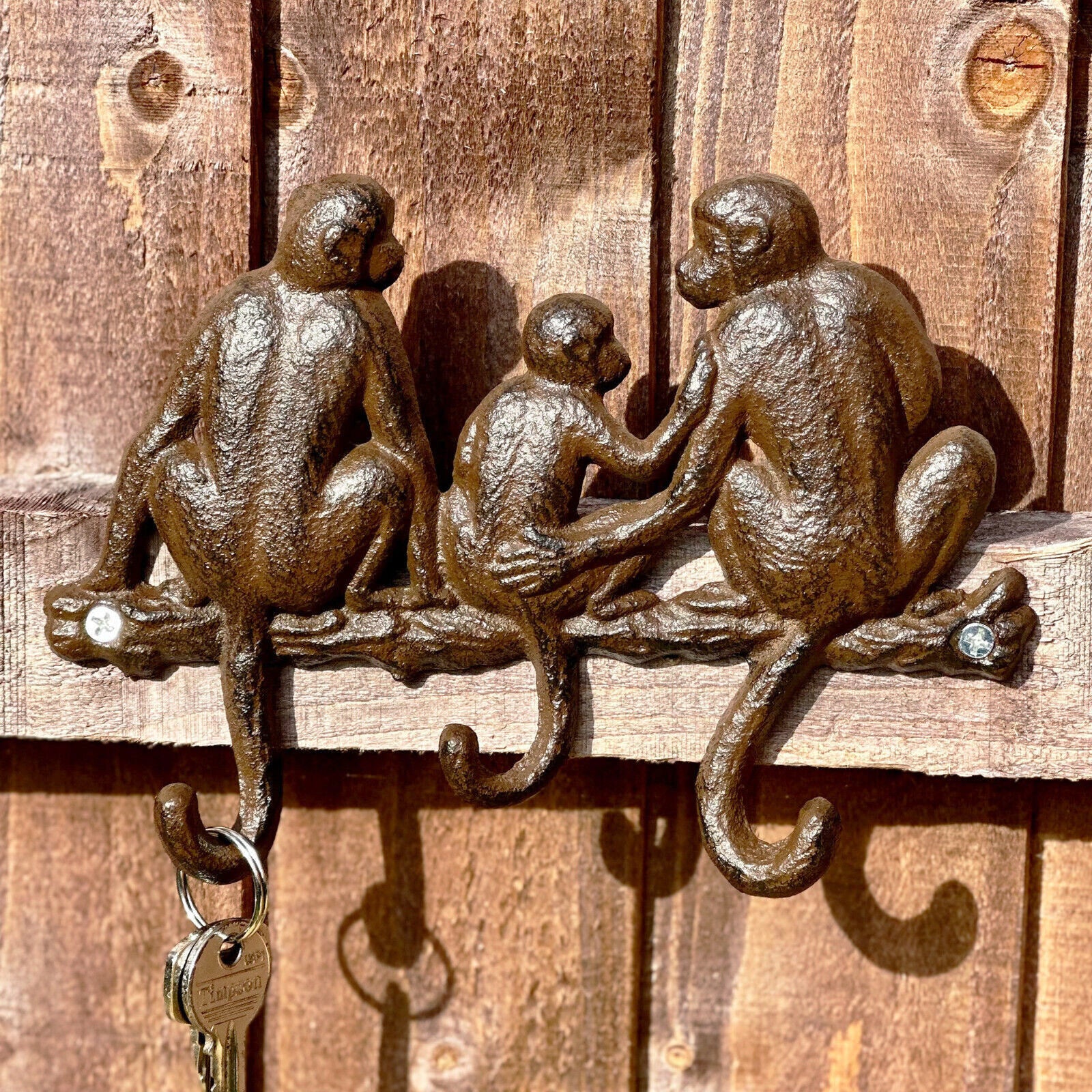 Wall-mounted cast iron hooks with a design featuring three monkeys sitting and facing forward.