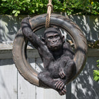 Gorilla figure sitting in a tyre swing with greenery in the background