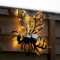Metal wasp wall art with string lights on a wooden background