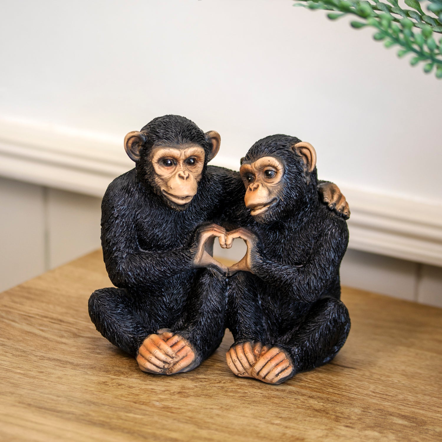 Two monkey figurines holding a heart-shaped object on a wooden surface.