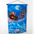 A fabric wall hanger featuring a colorful illustration of Santa's sleigh with reindeer, set against a blue moonlit night sky. The wall hanger is hung by a black rod and has a festive design with 'Christmas' written at the top.
