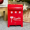 A red metal Christmas post box with white snowflake motifs, labeled 'To Santa North Pole'.
