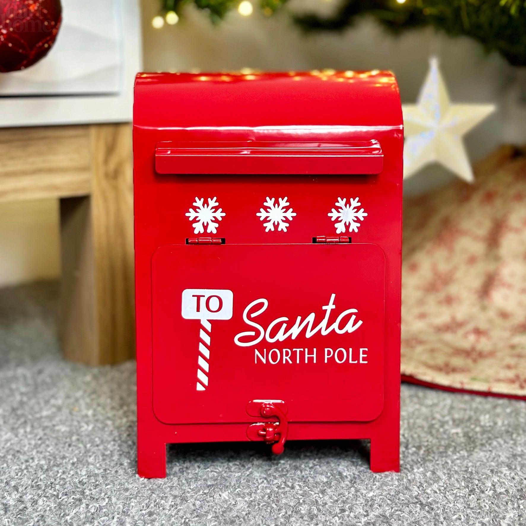 A red metal Christmas post box with white snowflake motifs, labeled 'To Santa North Pole'.