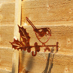 A copper effect steel bird feeder hanger shaped like a perched robin, mounted on a wooden fence.