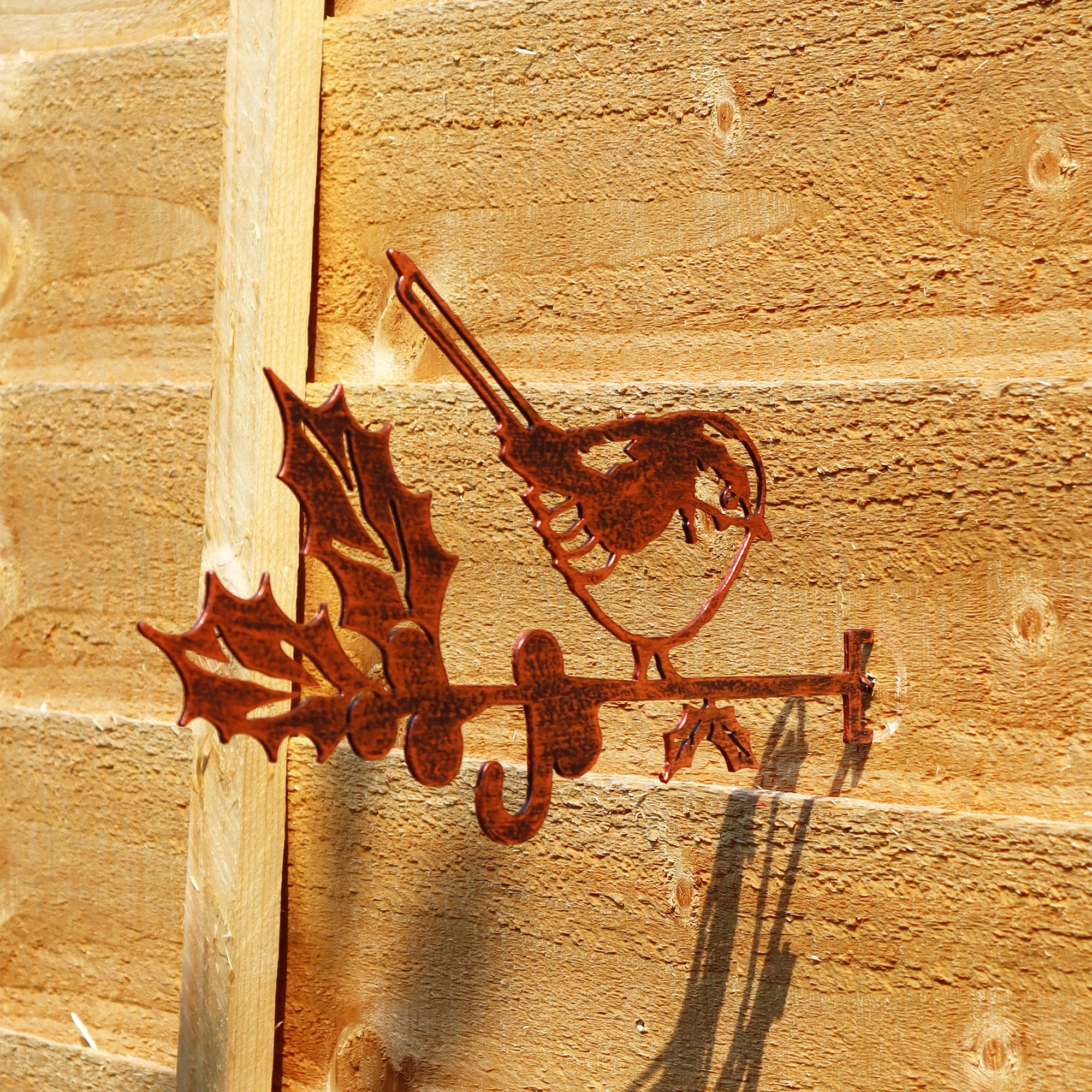 A copper effect steel bird feeder hanger shaped like a perched robin, mounted on a wooden fence.