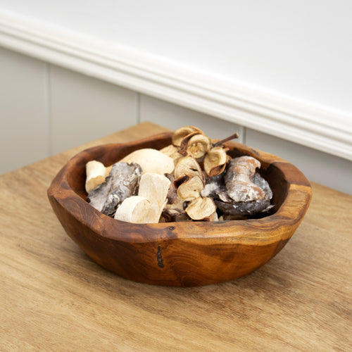 A rustic teak root wood bowl filled with decorative items, placed on a wooden surface.