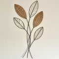 A wall-mounted metal art piece featuring woven wicker leaves in brown and black colors.