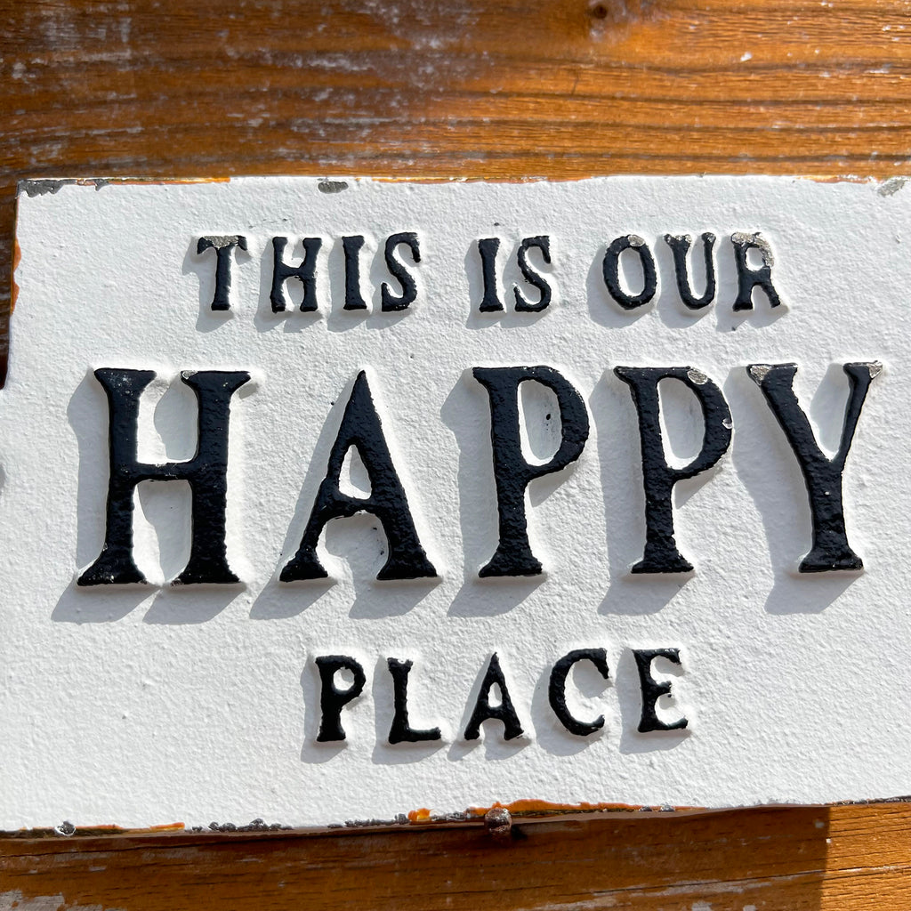 Weißes Gusseisen-Schild „This Is Our Happy Place“.